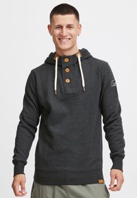 Sudadera gris de tejido suave, con una tapeta de botones en el frente con botones de madera, capucha ajustable con cordón y parche decorativo con logo.