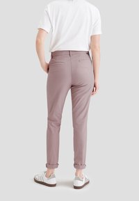 Ljus mauve-byxor med skräddarsydd passform, uppvikta fållar och två bakfickor, kombinerat med vita sneakers och en avslappnad vit t-shirt.