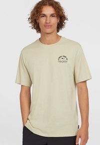 Beige katoenen t-shirt met een ronde hals, korte mouwen en een klein zwart logo op de bovenste linker borstpartij. Soepele textuur, relaxed fit.
