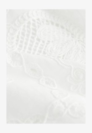 White embroidered fabric featuring intricate floral and circular patterns with a smooth texture. The design incorporates subtle raised stitches.