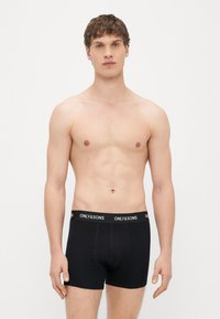 Mustad bokserid elastse vööga, millel valged "ONLY & SONS" tekstid. Riie on sile ja tihedaltistuv, õmblused on minimaalsed.