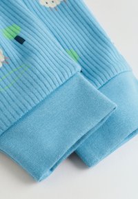 Tela acanalada azul claro con puños y pequeños estampados de flores y árboles en verde, blanco y azul oscuro.