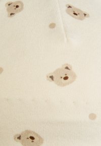 Cream fabric with a repeating pattern of small, simple teddy bear faces and dots in light brown tones.
