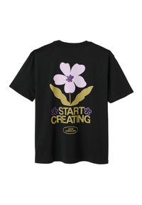 T-shirt noir avec graphique d'une grande fleur violette et de feuilles vertes, texte "COMMENCEZ À CRÉER," et plus petit "ARRÊTEZ DE DÉFILER" sous le dessin.