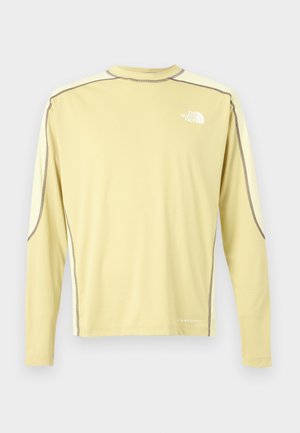 Chemise de performance à manches longues jaune clair avec surpiqûres contrastantes marron et logo blanc The North Face sur la poitrine ainsi que le texte "LIGHT RANGE" près de l'ourlet.