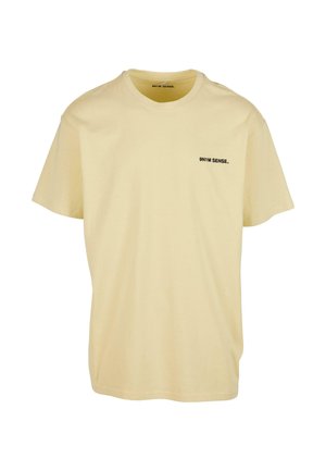 Kortærmet t-shirt med rund hals i lysegul bomuld, med et lille sort logo på venstre bryst. Blød tekstur og afslappet pasform.