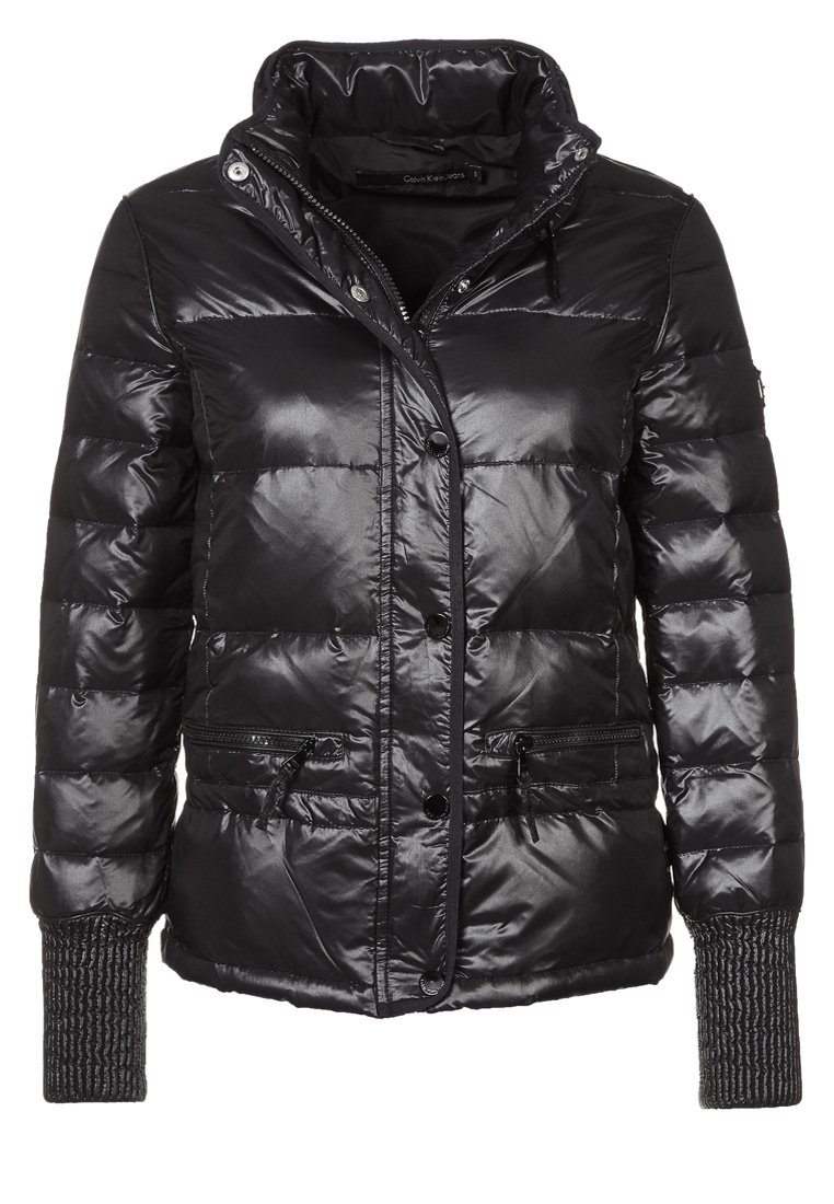 Svart pufferjacka i glänsande, quiltat material. Har hög krage, tryckknappar, fickor med dragkedja och strukturerade stickade muddar.