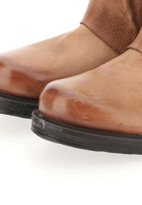 Bottes de cheville en cuir marron avec une finition lisse, bout rond et semelle en caoutchouc noir. Présente des plis discrets et un col texturé.