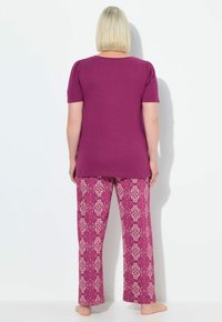 Top corto de manga corta púrpura con hombros abullonados combinado con pantalones rosas estampados con un diseño floral. Textura suave, ajuste relajado.