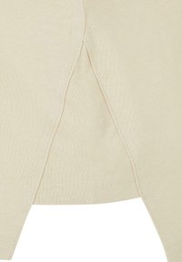 Top din bumbac bej, cu fante laterale, textură netedă, detalii cusute și un design casual. Cusătură vizibilă pe margini.