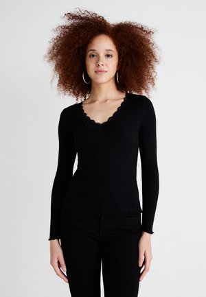 Black long-sleeve top with a scalloped neckline and hem, featuring a fitted design and ribbed texture. Accentuated with delicate lace trim.