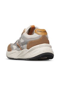 Baskets avec une tige textile gris clair, des accents en daim marron et une semelle blanche tachetée. Présente des détails orange et un logo circulaire à l'arrière.