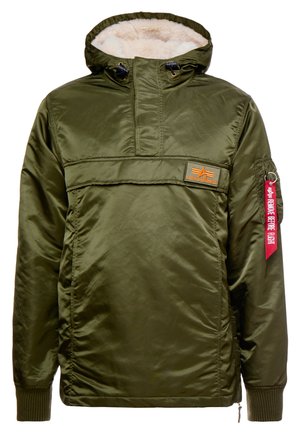 Olivově zelená, voděodolná bunda s kapucí s kožíškem, předním zipem a velkou kapsou. Obsahuje červenou textilní nášivku s nápisem "ODSTRANIT PŘED LETEM."