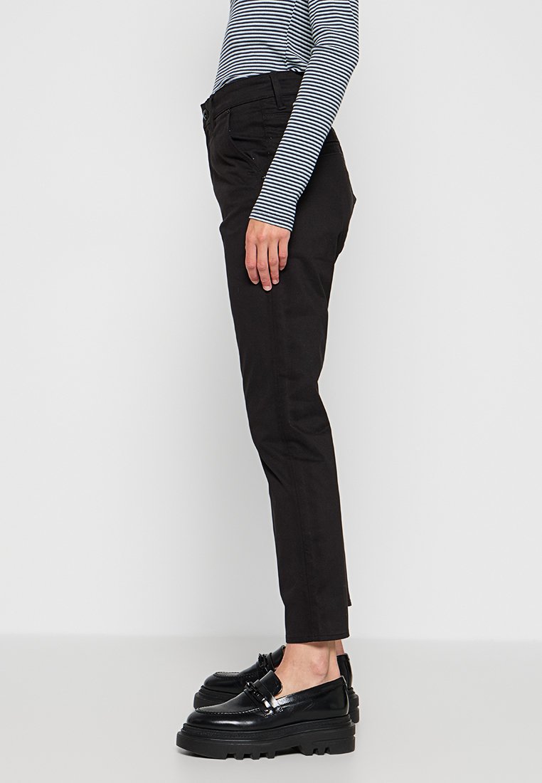 Pantalons noirs sur mesure, coupe slim, avec des détails de poches, associés à des mocassins noirs épais et un haut à rayures bleues marine à manches longues.