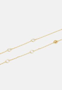 Eine goldene Kettenarmband mit runden klaren Edelsteinen in Abständen, das ein schlichtes Design mit glänzender Oberfläche und zarten Gliedern zeigt.