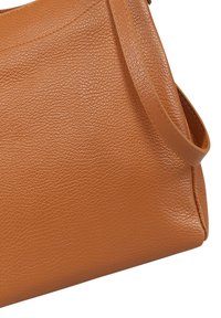 Brown leather handbag with a textured surface, rounded shape, and a single strap. Stitching details are visible along the edges.