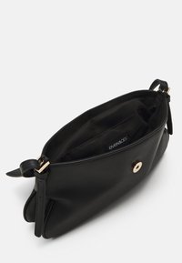 Sac à main en cuir noir avec un design plissé, quincaillerie dorée et une étiquette intérieure. Texture lisse avec une fermeture magnétique unique.