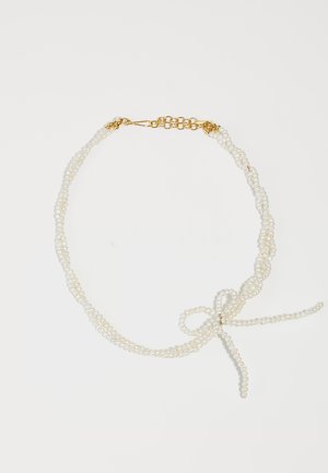 Collar de perlas blancas con múltiples hebras, que presenta un cierre de oro y un detalle de lazo hecho de hebras. Textura suave, diseño elegante.