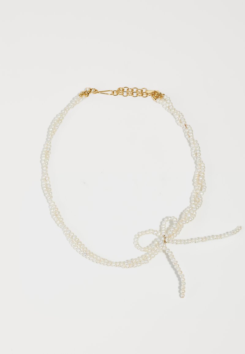 Λευκή πέρλα κολιέ με πολλές σειρές, διαθέτοντας χρυσό κούμπωμα και λεπτομέρεια σε φιόγκο φτιαγμένο από σειρές. Απαλή υφή, κομψός σχεδιασμός.