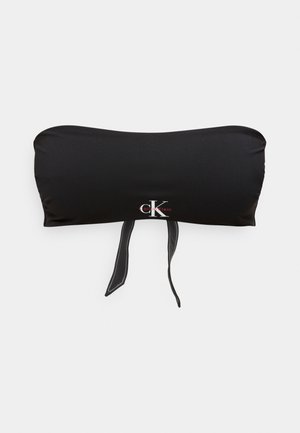 Haut de bikini bandeau noir avec logo Calvin Klein et deux fines bretelles pendantes sur fond blanc.
