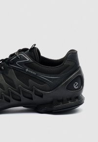 Baskets noires en Gore-Tex avec superpositions en mesh et synthétique, semelle texturée, design à lacets et languette de traction sur le col rembourré.
