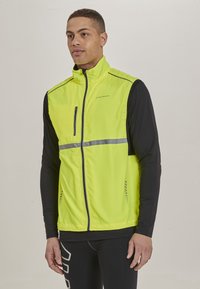 Helle gelbe, leichte Jacke mit vollem Reißverschluss, reflektierender Strecke und schwarzen Ärmeln. Netzakzente sorgen für Belüftung.