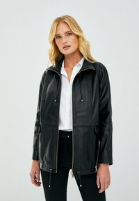Giubbotto in pelle nera con zip frontale, cappuccio regolabile con cordino, tasche laterali, texture liscia e dettagli in metallo dorato.