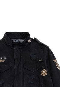 Zwarte denimjas met een hoge kraag, meerdere voorzakken en patchdetails. Versleten textuur met een houndstooth voering.