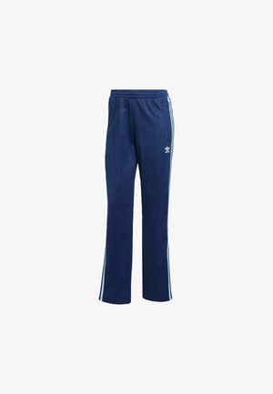 Pantalones deportivos Adidas azul marino con cintura elástica, rayas blancas laterales, bolsillos con cremallera y logo de trébol Adidas en el muslo.