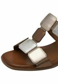 Brun sandal med metallisk silverdetaljer; har fyrkantiga remmar och en slät yta. Platt sula, öppen design för andningsförmåga.