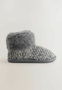 Grå strikslipper med et faux fur skaft, fleksibel sål og et vævet mønster med nuancer af grå og creme. Overdelen er blød og hyggelig.