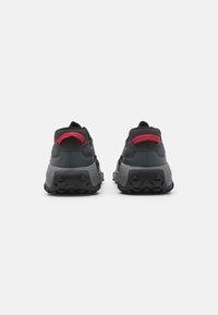 Schwarze und graue Sneaker mit strukturierter Oberfläche, roten Akzenten und robuster Laufsohle. Verfügt über einen gepolsterten Schaft und ein Logo an der Ferse.