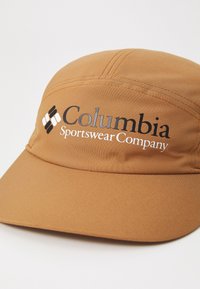 Barna sapka sima anyagból, állítható pánttal, ívelt billentéssel és fekete-fehér "Columbia Sportswear Company" logóval.