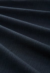 Tissu bleu foncé avec une texture lisse, présentant des rides douces et subtiles ainsi qu'un motif de tissage cohérent. Adapté à diverses applications.