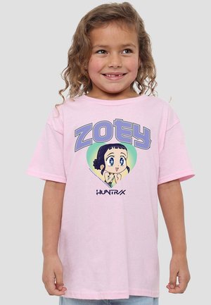 Young girl with curly hair smiles wearing a pink T-shirt featuring a cartoon character and the word "ZOEY" in large letters.
