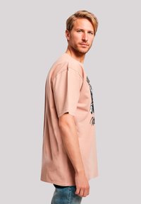 Light pink cotton t-shirt with short sleeves, featuring a graphic print on the front. Relaxed fit and simple crew neckline.