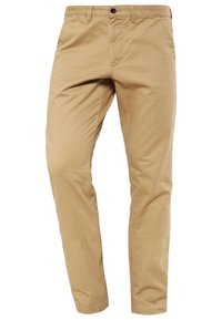 Chinos en coton beige à coupe droite, avec braguette zippée, fermeture par bouton et poches latérales. Texture lisse et design épuré.