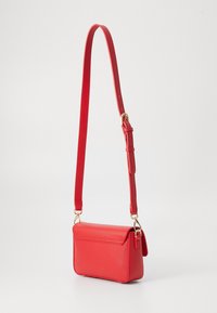 Borsa a tracolla in pelle sintetica rossa con tracolla regolabile, hardware dorato e chiusura a patta. Texture liscia e forma rettangolare.