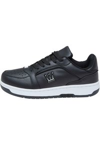 Svarte lærersneakers med rund tå, perforerte detaljer, hvit mellomsåle og en krone-logo på siden. Snøring foran.