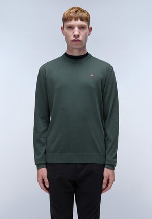 Groene lange mouwen trui in een zachte breimateriaal, met een ronde hals en een klein logo accent op de borst. Gecombineerd met donkere broeken.