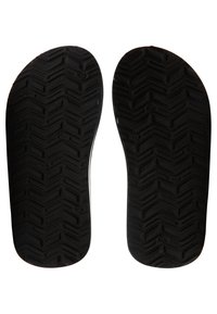 Sorte skosåler med et tekstureret zigzag mønster. Sålerne er flade, med afrundede kanter og en glat overflade langs siderne.