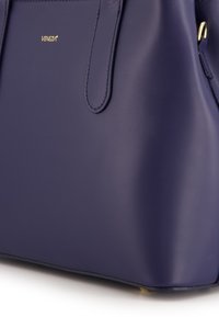 Hellblau synthetische Handtasche mit glatter Textur, zwei Griffen und goldenem Logoakzent. Einfaches und strukturiertes Design mit flachem Boden.