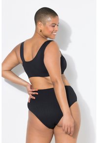Costume da bagno a due pezzi nero a coste con top corto a spalline larghe e pantaloni a vita alta, che mostrano un design in tessuto testurizzato.