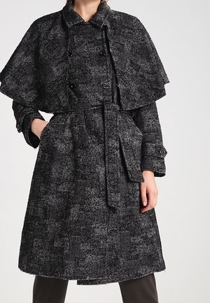 Zwart-wit gemarmerde wollen jas met een cape-ontwerp, een tailleriem en knoopaccenten. Lange mouwen met knoopdetails op de manchetten.