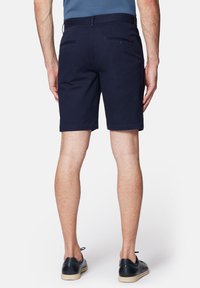 Granatowe szorty wykonane z bawełny, charakteryzujące się prostym krojem, dwoma tylnymi kieszeniami z zapięciami na guziki oraz gładką fakturą.