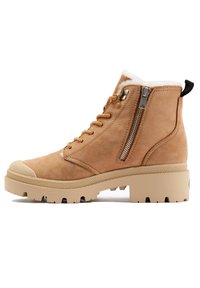 Bottines en daim beige avec une semelle en caoutchouc texturé, dotées d'une fermeture éclair sur le côté et d'un laçage. Doublure douce au niveau de la cheville pour plus de confort.