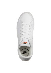 Bílé kožené tenisky Nike s tkaničkami, kulatou špičkou, polstrovanou stélkou a malým oranžovým logem Nike na jazyku a boku.