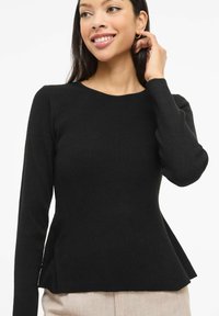 Czarna prążkowana bluzka z długim rękawem, okrągłym dekoltem i rozszerzanym dołem. Tkanina ma lekko teksturowany wygląd. Nadaje się do codziennego noszenia.