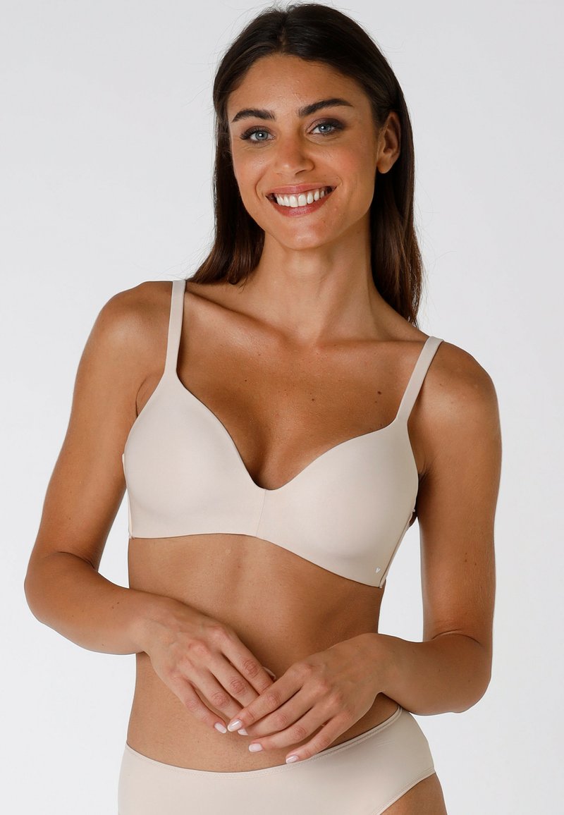 Reggiseno imbottito beige con scollatura profonda, spalline regolabili e texture liscia. Design senza cuciture e stile minimalista ben evidenti.