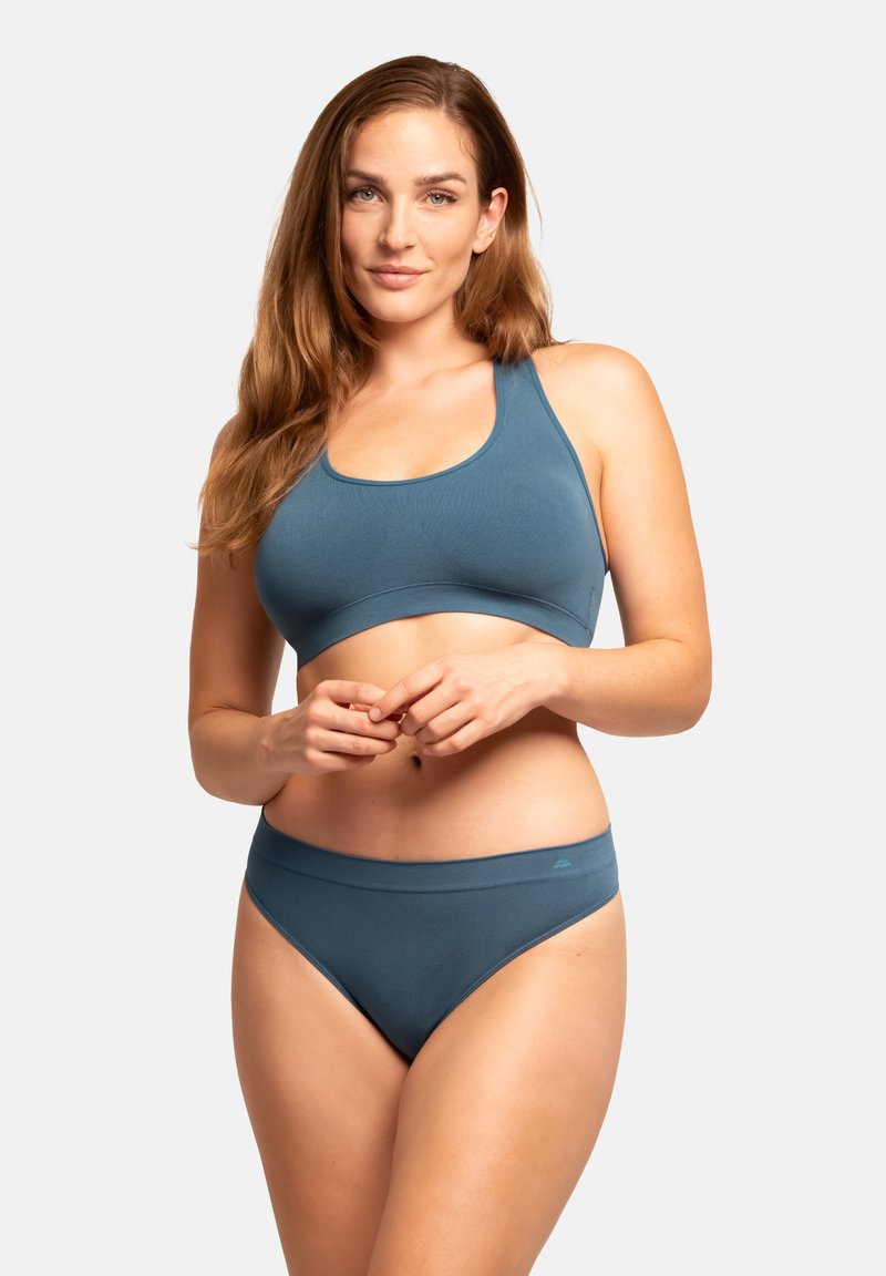 Teal sportbh och matchande trosor gjorda av slät tyg. Bh:n har en rundad halsringning och tjocka band, medan trosorna har en bred midjeband.